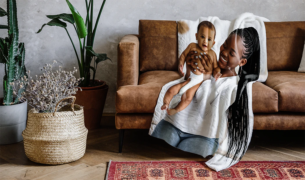 Gepersonaliseerde fotodeken: Moeder en baby knuffelen op een bruine bank. Een uniek, gekoesterd aandenken.