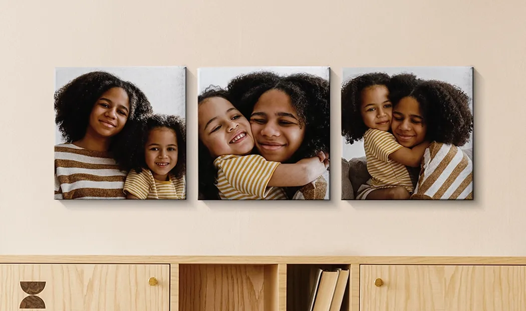 Foto Canvas Display Panelen van Printerpix|Canvas Panelen|Man en vrouw die een fotocanvas ophangen met een vakantiefoto|Vrouw die drie zwart-wit familiefotocanvassen ophangt|Moeder en vier jonge kinderen zitten op de bank voor vier fotocanvassen|Koppel voor een blauwe muur met negen vierkante fotocanvassen|||||