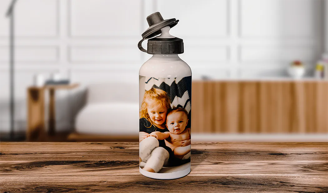 Gepersonaliseerde Fotoflessen|Gepersonaliseerde waterfles; wit, met een foto van een kind, zwarte klapdeksel. Uniek cadeau!|Gepersonaliseerde flamingo waterfles op zandstrand, naast zonnebril & hoed. Perfect zomergeschenk!|Gepersonaliseerde waterfles met kleurrijk ontwerp & leuke quote, perfect voor bruiloften. #Sophie&Brad